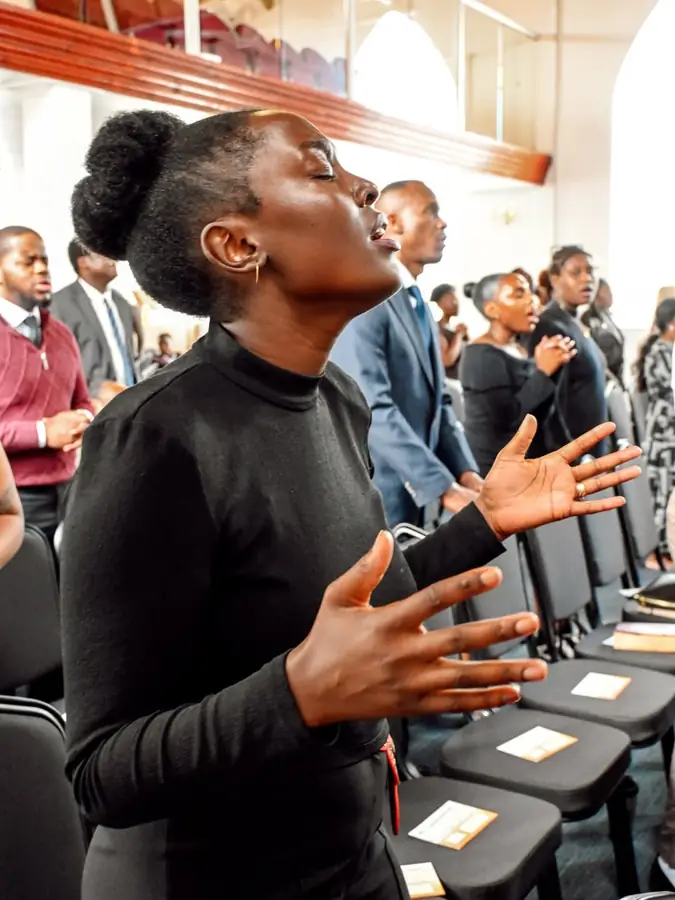 A woman worshipping with her eyes closed and hands open